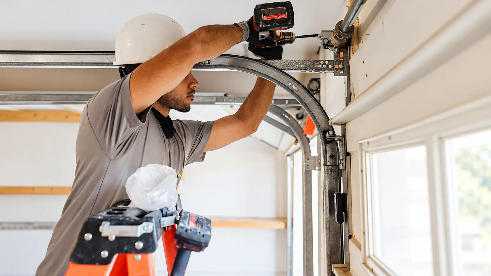 Technician working on a garage door track and repair hardware