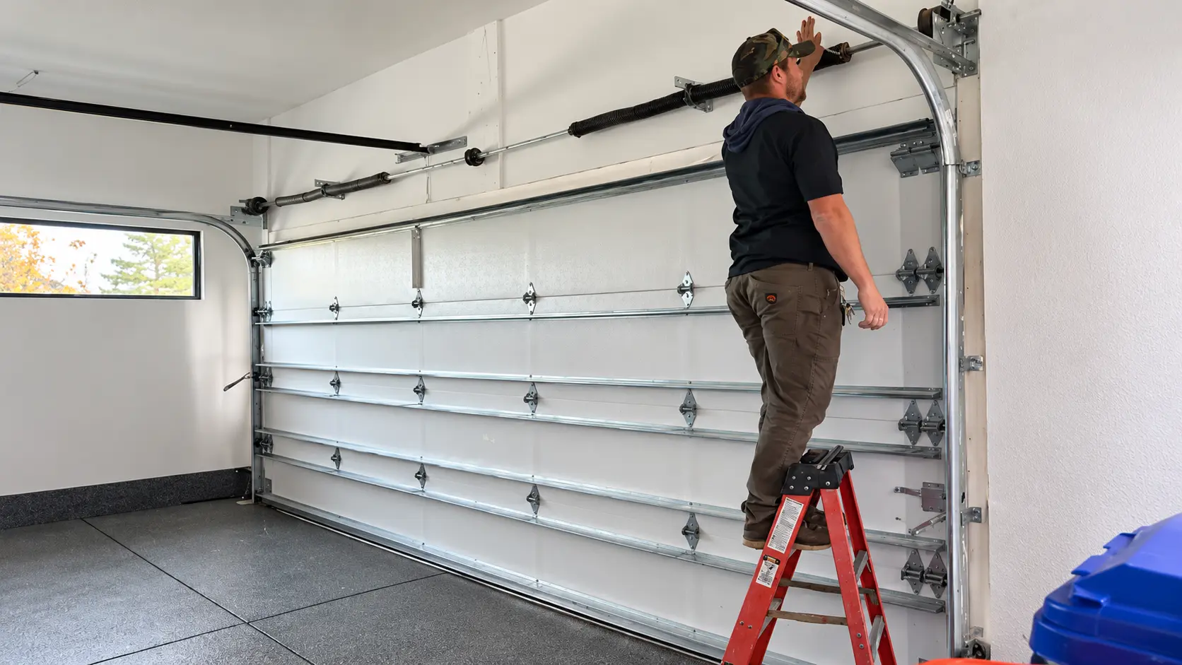 Technician examining a residential garage door and its operating hardware
